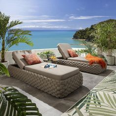 an outdoor living area with two couches and a coffee table on the patio overlooking the ocean