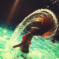 a woman is in the water with her hair blowing