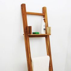 a wooden ladder shelf with soap, lotion and toothpaste on it next to a white wall