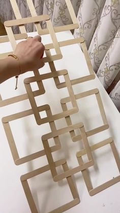 a person is holding a piece of wood that has been cut into squares and placed on top of a table