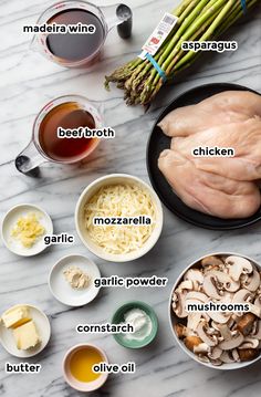 ingredients to make chicken broth laid out on a marble counter top, including asparagus, garlic, mushrooms, butter, and seasonings