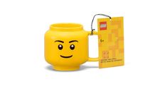 a yellow mug with a smiley face on it and a card in front of it