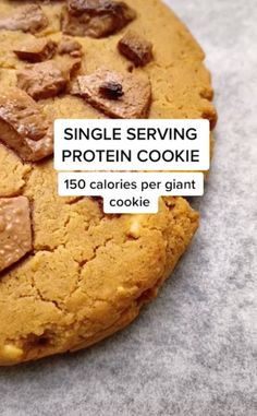 a close up of a cookie on a table with the words single serving protein cookie above it