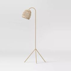 the floor lamp is made out of wood and has a woven shade on it's head