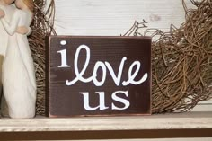 a wooden sign that says i love us next to a figurine on a shelf