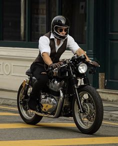 a man riding on the back of a motorcycle down a street