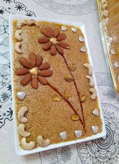 a square white plate topped with lots of nuts and flower decorations on top of a table