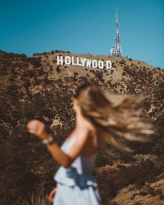 a woman running in front of the hollywood sign with her hair blowing in the wind