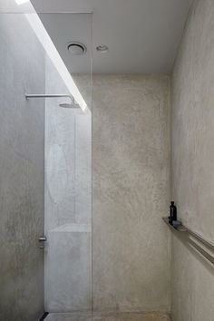 a walk in shower sitting next to a white wall and tiled floor with a skylight above it