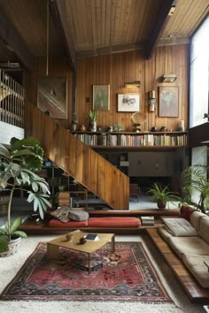 a living room filled with lots of furniture next to a stair case and bookshelf