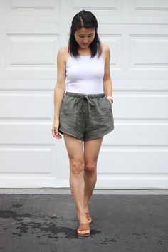 a woman wearing shorts and sandals standing in front of a garage door