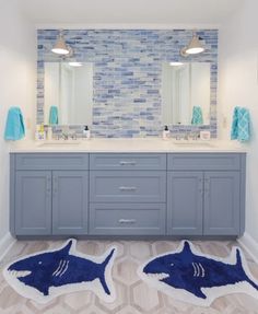 a bathroom with blue and white tiles on the wall, two sinks and mirrors in it