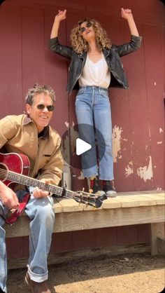 a woman sitting on a bench next to a man holding a guitar