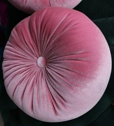 two pink and green velvet cushions sitting next to each other on top of a black chair