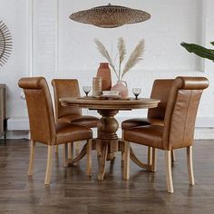 a dining room table with chairs and a vase on it's centerpiece in front of a white brick wall