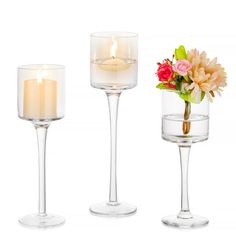 three wine glasses with candles and flowers in them