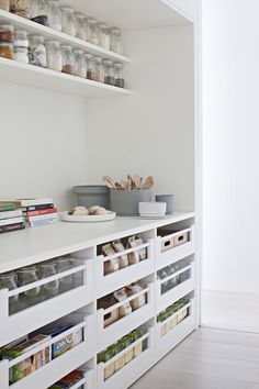 a kitchen with white cabinets and shelves filled with food