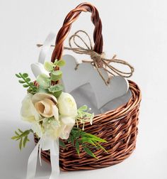 a wicker basket with flowers and a heart shaped box in the center on a white background