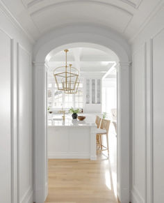 an archway leading into a kitchen with white walls and wood flooring on the side