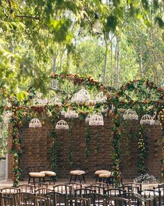 tables and chairs are set up in front of a brick wall with hanging chandeliers