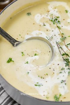 a spoon in a bowl filled with soup and garnished with fresh parsley