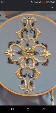 an embroidery project is being displayed on a blue tablecloth with gold trimmings