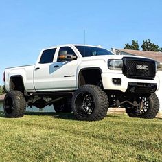 a white truck parked on top of a lush green field