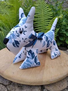 a stuffed dog sitting on top of a wooden table next to green plants and bushes