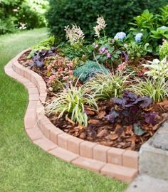 a garden with flowers and plants growing in the ground next to a brick planter