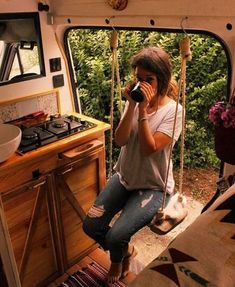 a woman sitting in the back of a van talking on a cell phone while holding a camera