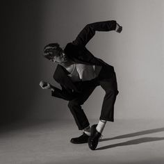 a man in a tuxedo is doing a dance move with one foot on the ground