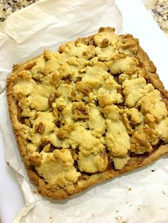 a square piece of food sitting on top of a white sheet of paper next to a knife