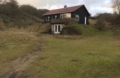 a black house sitting on top of a lush green hillside