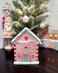 a small pink gingerbread house next to a christmas tree