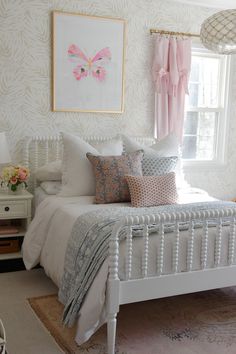 a white bed sitting in a bedroom next to a window with pink curtains on it