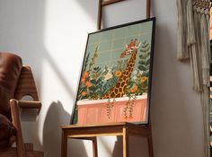 a giraffe standing in front of a painting on a easel next to a chair