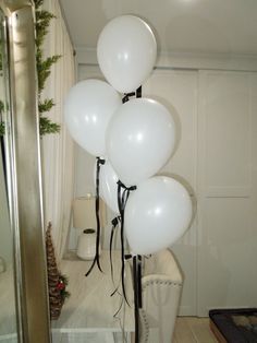 white balloons are tied to the ceiling in front of a mirror and christmas garlands