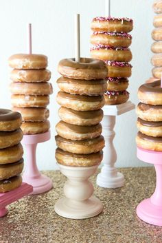 donuts stacked on top of each other in pink and white dishes with candles sticking out of them