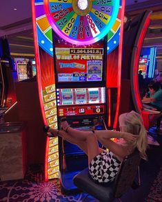 a woman is sitting in front of a slot machine and playing the game with her legs spread out