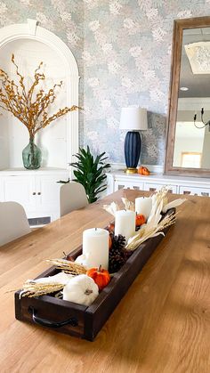 a wooden table topped with candles and pumpkins