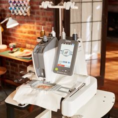 a sewing machine sitting on top of a white table next to a brick wall in a room