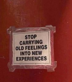 a sign posted on the side of a red door stating to stop carrying old feelings into new experiences