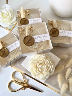 four boxes with flowers and some scissors on top of a table next to other items