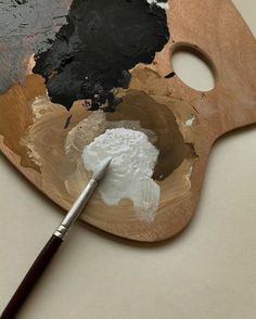 a paintbrush is sitting on top of a wooden palette with black and white paints