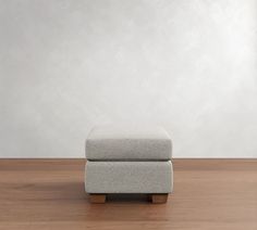 a small footstool sitting on top of a wooden floor next to a white wall