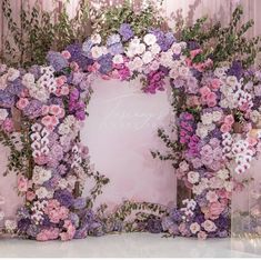 a pink and purple flowered photo frame with flowers on the front, along with greenery in the back