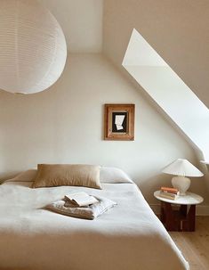 a white bed sitting under a window next to a lamp