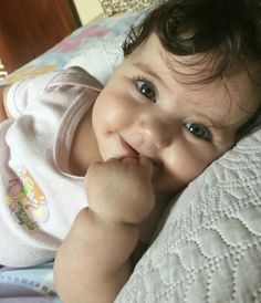 a smiling baby laying on top of a bed