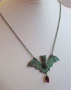 "Vampire Bat Necklace - Siam Faceted Crystal Glass Jewel in Antiqued Brass Setting dangles from a Verdigris Patina Brass Bat. The jewel looks like a droplet of blood. Bat measures just under 2.75\" wide x just over 1.25\" tall (excluding jewel) 24\" Brass Chain This is a stock photo. Each piece is unique. The verdigris will vary from the one pictured. For other bat designs: https://www.etsy.com/shop/mcstoneworks?ref=l2-shopheader-name&search_query=bat Be sure to check out my Patina Collectio Vampire Style Halloween Necklace For Jewelry Making, Handmade Vampire Jewelry For Halloween, Vampire Style Necklace For Halloween, Handmade Vampire Style Party Necklace, Collectible Vampire Jewelry For Halloween, Handmade Vampire Style Jewelry For Cosplay, Vintage Costume Necklaces For Halloween, Handmade Vampire Jewelry For Cosplay, Handmade Vampire Style Necklace For Gift