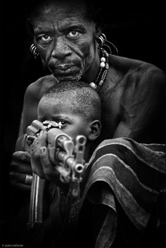 a black and white photo of a man with a child on his lap looking at the camera